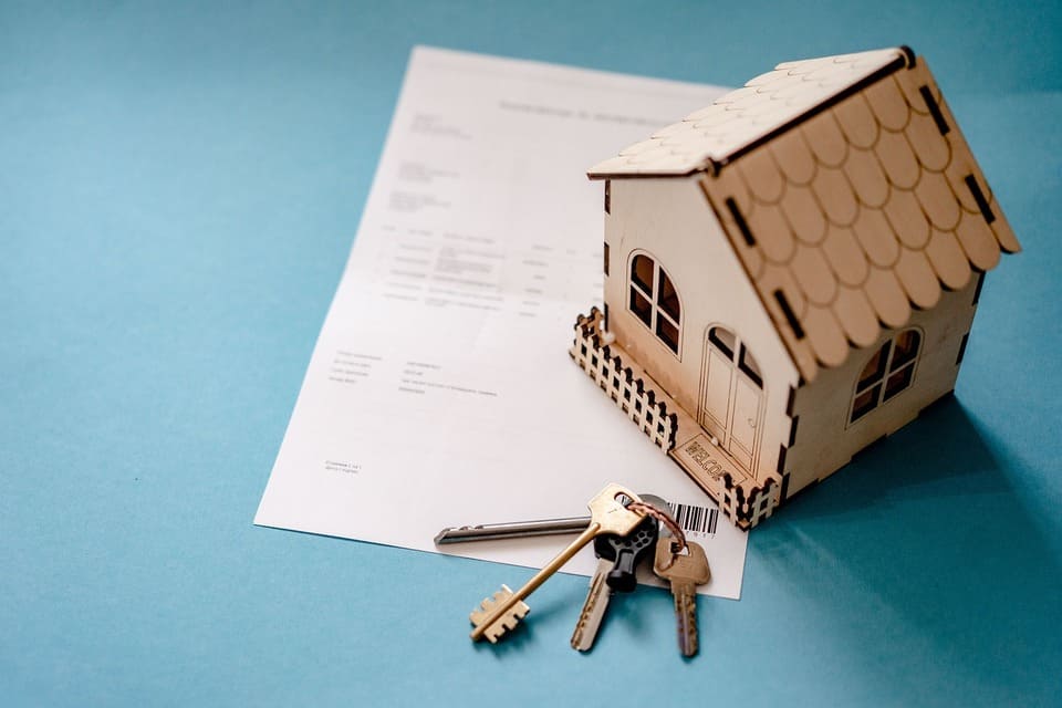 model-of-a-house-and-keys-on-top-of-a-real-estate-document