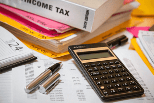 calculator and pens on top of tax forms