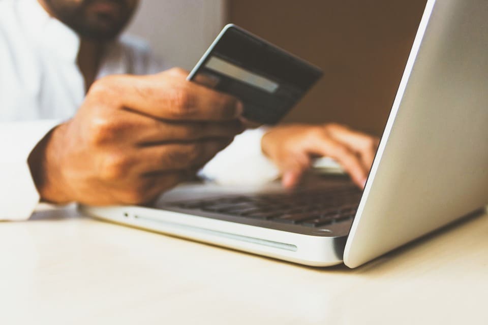 man-typing-on-a-laptop-while-looking-at-a-credit-card