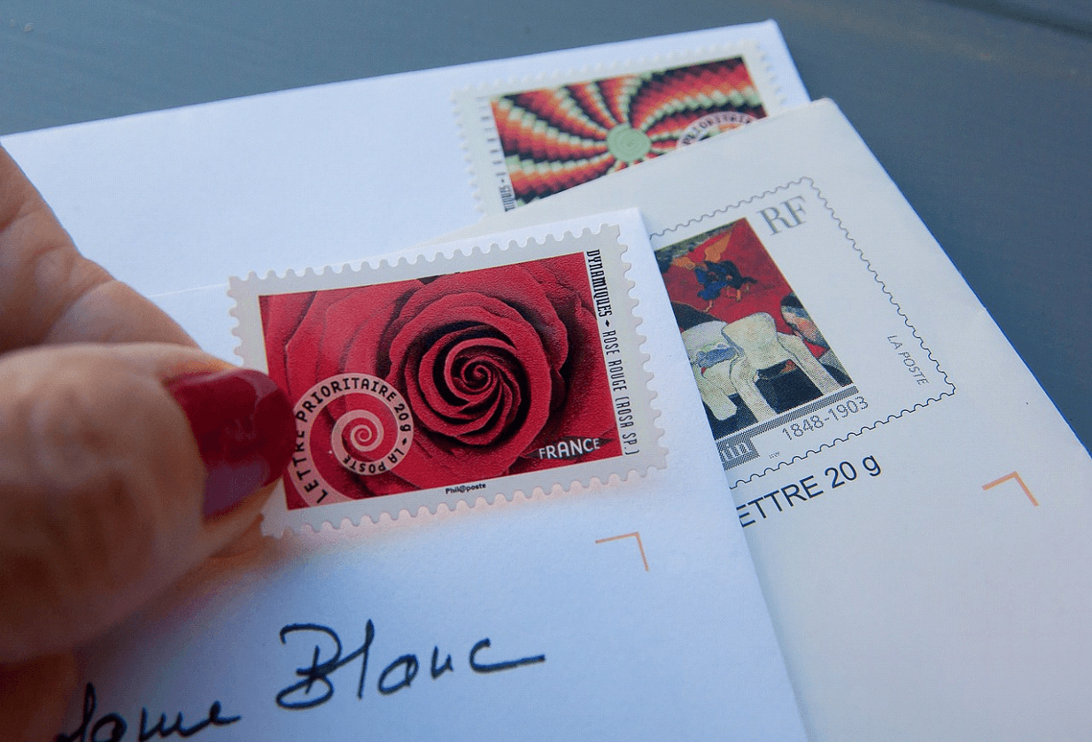 person putting stamps on mail envelopes